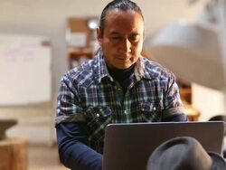 Native American artist using laptop in his art studio Stock Footage