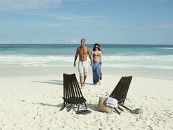 Couple walking on sandy beach and sitting on deck chairs Stock Footage