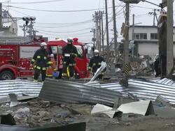 Destruction caused by tsunami after magnitude 9 Tohoku earthquake, north east Japan, March 2011. Fire crews walk over debris in Ishinomaki City,  Miyagi Prefecture Stock Footage