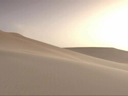 Wide Shot, pan-right - The golden sun hangs in the sky over the Sahara Desert in Egypt Stock Footage