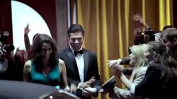 Cameras flash as celebrity couple leaving awards show walk red carpet to limousine at awards show Stock Footage