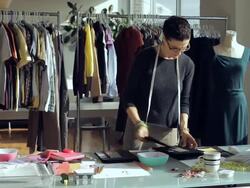 MS TD PAN Fashion designer working at desk while sorting through clothing racks/ New York City, New York, USA Stock Footage