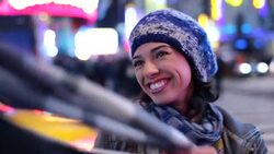 Cute young woman plays with boyfriend's scarf on Times Square street-corner Stock Footage