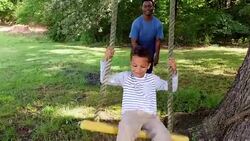 MS Smiling young boy being pushed on swing by father in backyard Stock Footage