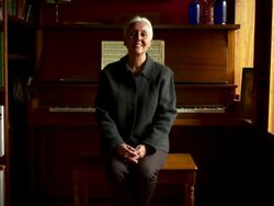 Slow dolly out on portrait of woman sitting on piano bench. Stock Footage
