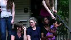 MS Lesbian couple sitting with family on front porch of home on summer evening Stock Footage