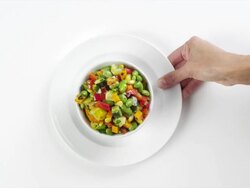 CU Woman hand entering setting down round white plate with edamame bean salad / Omaha, Nebraska, United States Stock Footage
