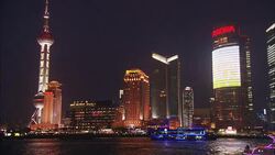 Brilliant neon lights illuminate water front skyscrapers and ferry boats in Shanghai. Stock Footage