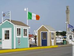 pier houses on the wharf of Provincetown Cape Cod with the Pilgrim monument in background Stock Footage