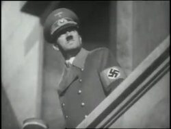 German Chancellor Adolf Hitler stands on a balcony watching Nazi soldiers march by carrying torches. News Clip