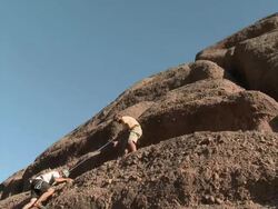 Man rock climbing as other climber helps him up, they high five Stock Footage