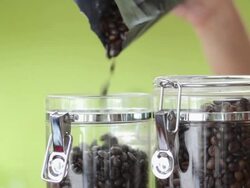 Coffee beans are poured in the glass jar Stock Footage