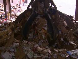 A claw grappler lifts a large ball of paper and paper products in a recycling facility. Stock Footage