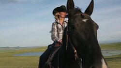 Female rancher sitting horseback in sunny rural field Stock Footage