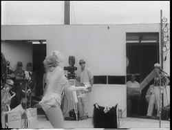 B/W 1967 blonde woman in costume twirling + throwing burning batons in USO show / Vietnam War Stock Footage