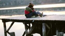 A loving couple in a warm hug on a dock with a baby dog Stock Footage