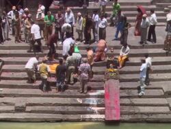 WS Men gathering  around corpse laid on steps of  river during funeral proceedings  / Kathmandu, Central, Nepal Stock Footage