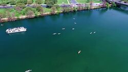 looking straight down at kayakers moving fast. Flying over the Middle of Lake Aerial View Austin Texas Colorado River Fun Spring water activities with kayakers and Party Boat during SXSW Spring Break 2016 Stock Footage