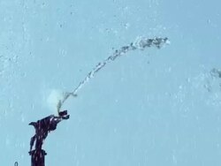 Slow motion Water shoots from an irrigation head through the air against a blue sky Stock Footage