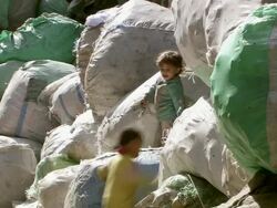 MS Shot of two children playing on packed recyclable materials bags / Cairo, Egypt Stock Footage