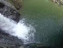 A young man cliff jumping into a river next to a waterfall.  - Slow Motion - filmed in Munich, Germany, Europe Stock Footage