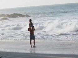 MS Man and boy on beach looking out at wave break with seamist in air / Montezuma, Puntarenas, Costa Rica Stock Footage