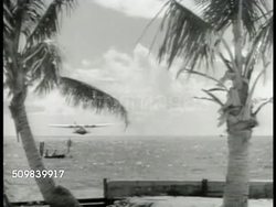 1939: US TERRITORY OF GUAM: Pristine Port Apra harbor w/ Cruiser docked offshore harbor boat moving FG. EXT US Navy building. Clipper coming in for landing on water off screen (R). Spanish-American War cannon. Port Apra harbor. Instructional Video