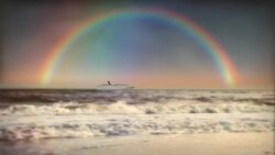 Waves crash to the shore as a cruise ship sails underneath a beautiful reflection of a rainbow. Stock Footage