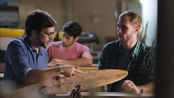 Wood shop craftsman points out design details of custom longboard to pupil Stock Footage