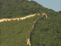 Pan left across hillside to overgrown and decaying section of Great Wall of China, Mutianyu, China Stock Footage