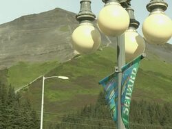 "Lampost banner with ""SEWARD"" and salmon design, rounded white lamps and green mountain, 4th Avenue, Seward, Kenai Peninsula, Alaska" Stock Footage