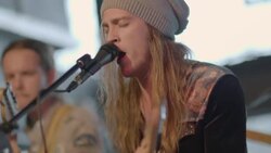 Long-haired guitarist sings into microphone with band at live music showcase Stock Footage