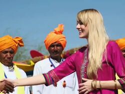 Young woman shaking hands with indian folk dancers, Suraj Kund, Faridabad, Haryana, India Stock Footage