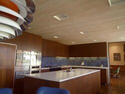 DS through mid-century modern kitchen in country club home from 1971 with space age kitchen lamp, white tiled counter tops, wood paneled kitchen cabinets and built-ins Stock Footage