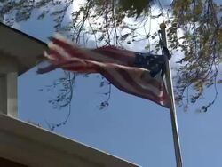 Tattered Stars and Stripes flag flying on flagpole News Clip