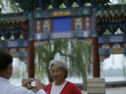 MS TD Mature man taking a photo of elderly woman in front of traditional Chinese gate / Beijing, China Stock Footage