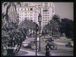 1953: LOS ANGELES, CALIFORNIA: XWS City from hillside community, possibly Hollywood Hills. Angled WS Large building on curved street w/ palm trees, VS Street scenes w/ modern buildings, light traffic.      Downtown, hotel, apartments, Coulter building Instructional Video
