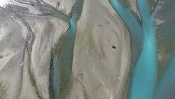 Aerial long shot of a Brown Bear walking up a river looking for fish Stock Footage