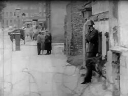 B/W 1961 PAN from soldier leaning against wall to soldiers walking by barbed wire of Berlin Wall Stock Footage