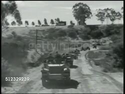 1942: U.S. MARINE CORPS: MOBILIZING CONVOY: (POV truck) VS Military trucks driving on road, hills BG. (POV truck) Trucks driving through forest path, cannon FG. WS Marine transport trucks on road. Military vehicles. Instructional Video