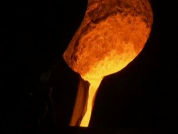 Molten metal poured from cauldron, tilt down to follow path of molten liquid(sound available) Stock Footage