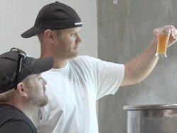 MS brew master and assistant holding up beer tasting glass with test brew above steaming boil kettle as they step closer to smell aromas of hops and malts / Thousand Palms, California, USA Stock Footage