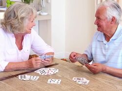 Senior couple sitting at table playing cards Stock Footage