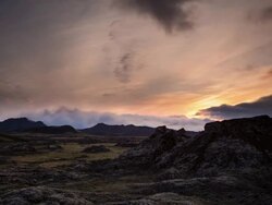 Sunset in Iceland during midnight sun out near Landmannalaugar with a lava dome in the foreground. Shot is wide with lava dome framed to the right. Stock Footage
