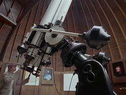 Low angle wide shot tilt down tilt up roof retracting as boy enters observatory / boy looking through telescope Stock Footage