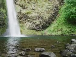 CU Shot of waterfall pours down green mountain into calm pool of water / Hood River, Oregon, United States  Stock Footage