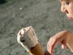 Girl eating an ice cream cone and smiling at camera Stock Footage