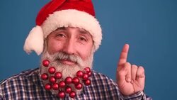 Senior adult man with a beard in elegant hat of Santa Claus showing copy space and thumb Stock Footage
