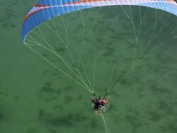 WS AERIAL SLO MO Shot of paramotor flying and skimming a lake in the french alps / chambery, savoir, france  Stock Footage