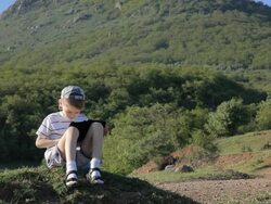 little boy sitting, reading e-reader on walk in mountain Stock Footage